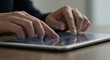 © Strive Studio - Hands touch a tablet screen on a table surface close up view.