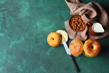 Wall Mural - Tasty bagels with almond nuts and jug of milk on green background