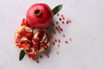 Wall Mural - Fresh ripe pomegranates with seeds and leaves on light background