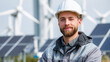 © Olga - Portrait of a young engineer in a white helmet, smiling, standing in front of modern wind turbines and solar panels. Clean energy, renewable technology