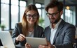 © cui - Business colleagues engaged in discussion over project ideas. Man holding tablet , woman pointing at laptop screen. Collaborative teamwork in modern office environment focused on planning strategy.