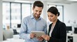 © twilight mist - Two business professionals collaborate, reviewing information on a digital tablet in a bright, modern office.