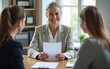 © wang - Smiling mature business woman hr holding cv document at job interview. Happy mid aged professional banking manager or lawyer consulting client sitting at workplace in corporate office meeting.