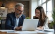 © hao - Business team of two executives working together using laptop in office. Happy young business woman manager showing project presentation to mature man client, investor or partner at work meeting.