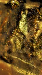 Wall Mural - Vertical video. Glossy abstraction. Wet texture. Defocused golden yellow colorful paint in water chemical fluid spilling on dark black bokeh background.