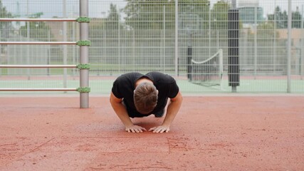 Wall Mural - Young man doing push ups on a red outdoor court, engaging in intense calisthenics training and building strength for a healthy lifestyle, low static camera, slow motion