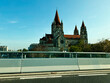 View of a grand cathedral St. Francis of Assisi with red roofs and twin towers from a bridge overlook in Vienna, Austria.