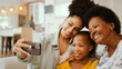 © Monkey Business - Multi-Generation Female Family Posing For Selfie On Mobile Phone Sitting On Sofa At Home Together
