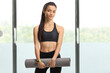 © Ljupco Smokovski - Young female holding an exercise mat in a gym