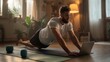 © Adib - Focused man performing plank exercise while following online fitness class on laptop in a cozy home setting