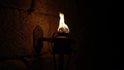 Sticker - timelapse of an ancient-looking torch burning brightly against a dark stone wall, fuel slowly consum