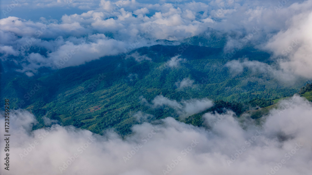 Aerial of Village in rain cloud cover tropical green mountain. Rainy season. Misty cover green forest. beautiful green village