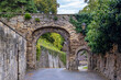 © Walter Riedinger - Two Ancient Stone Arches Covered In Ivy And Weathered Brick Create A Narrow Inviting Alleyway Between Historic Walls