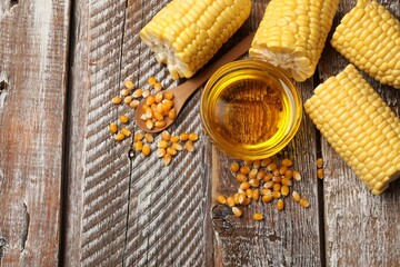 Wall Mural - Corn oil, kernels and cobs on wooden table, flat lay. Space for text
