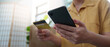 © Natee Meepian - Online Shopping. Woman holding smartphone and credit card for digital purchases.