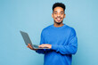 © ViDi Studio - Young IT man of African American ethnicity wears sweatshirt casual clothes hold use work on laptop pc computer isolated on plain pastel light blue cyan background studio portrait. Lifestyle concept