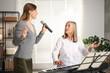 © New Africa - Woman learning to sing while her teacher accompanying on piano indoors