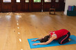 © wavebreak3 - Woman performing child's pose on bright blue mat in yoga studio near wooden doors, copy space