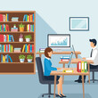 © Islah - Two people working at desks in an office setting, with bookshelves and plants.