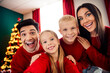 © deagreez - Happy family enjoying Christmas day together indoors, dressed in red sweaters, celebrating by a sparkling decorated tree