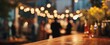 © Marta B - The wooden table in foreground at a blurred festive outdoor evening gathering