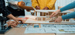 © InfiniteFlow - A diverse team of professionals engages in an architectural design meeting, reviewing blueprints and 3D models in a bright, modern workspace. SACTR