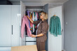 © okrasiuk - Middle aged woman selecting clothes from wardrobe for donating to Charity shop. Decluttering, Sorting clothes and Cleaning Up. Reuse, second-hand concept. Conscious consumer, sustainable lifestyle.