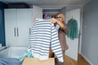 © okrasiuk - Woman putting selected clothes from her wardrobe for donating to a Charity shop. Decluttering, Sorting clothes and Cleaning Up. Reuse, second-hand concept. Conscious consumer, sustainable lifestyle