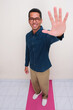© KrishnaTedjo - High angle view of adult asian man standing with happy face and showing 5 fingers sign