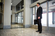© Wavebreak Media - Businessman wearing black suit standing near glass doors in lobby carrying briefcase, copy space
