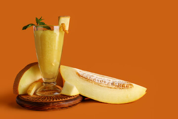 Wall Mural - Wooden board with glass of tasty melon smoothie and mint on brown background