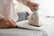 © Pixel-Shot - Young woman ironing bed sheets at home, closeup