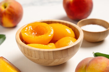 Wall Mural - Wooden bowl of tasty canned peaches and sugar on light background