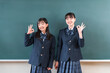 © buritora - 教室の黒板の前に立つ制服姿の友達,小学生,中学生,高校生の女子生徒