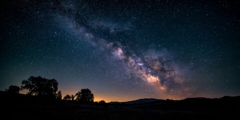 Wall Mural - Stunning Night Sky with Milky Way and Stars Over a Dark Silhouette Landscape at Night