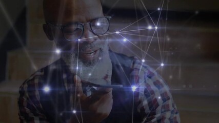 Mature man lifting smartphone and recording technology message with network nodes pulsing over face