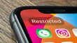 © Enjoy - Smartphone screen displays Restricted notification on social media app icon, symbolizing media ban