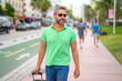 Mature man traveler outdoor. Tourist traveler on spring vacation. The travelers luggage for spring trip. Summer tour. A tropical getaway. Spring break. A traveler enjoys summer day. Summer trip.