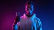 © zenith - Happy Young Man Smiling While Holding Smartphone with Neon Pink and Blue Gradient Background