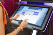 © EdNurg - Woman scanning barcode on self service kiosk with touch screen, using smartphone and printed receipt