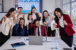 © Wasana - Excited business team celebrating success around laptop in office meeting