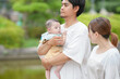 © Masakazu Tokashiki - A man is holding a baby in his arms while two women look on. Scene is warm and affectionate, as the man is showing love and care for the baby