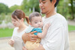 © Masakazu Tokashiki - A man is holding a baby in his arms. The baby is wearing a blue shirt
