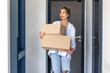 © puhimec - Young woman holding two boxes in hallway. Home delivery.