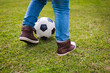 © wavebreak3 - School-age boy balancing black-and-white soccer ball on grass wearing jeans and sneakers