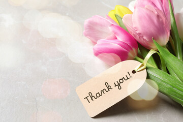 Thank tag and tulip flowers on grey table. Bokeh effect