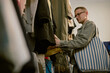 © Westend61 - Customer choosing clothes at vintage store holding striped bag