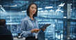 © Gorodenkoff - Asian Female Systems Administrator Standing in a Glass Office, Using a Tablet Computer at Work in a Technology Center. Empowering Leading Specialist Posing, Looking for Camera and Smiling