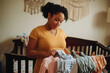 © Starmarpro - Pregnant woman preparing nursery, arranging baby clothes, excited for new arrival, expectant mother nesting and getting ready for baby.