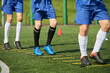 © Mediaphotos - Group of teenage boys training on outdoor sports field, performing agility ladder drills, legs and lower bodies visible, wearing athletic uniforms, focusing on coordination exercise